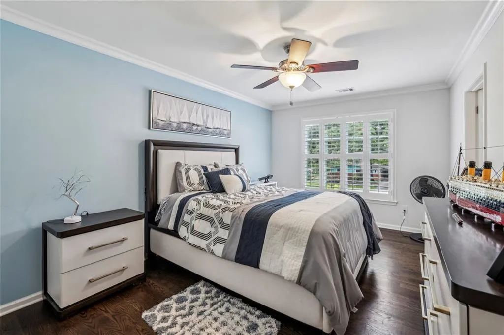 Bedroom with ornamental molding, dark wood-type flooring, and ceiling fan