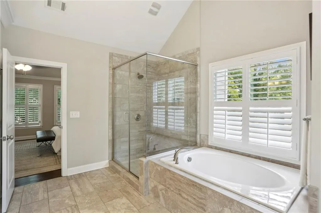Full bathroom featuring tile floors and both a walk-in shower and garden tub, and high vaulted ceiling