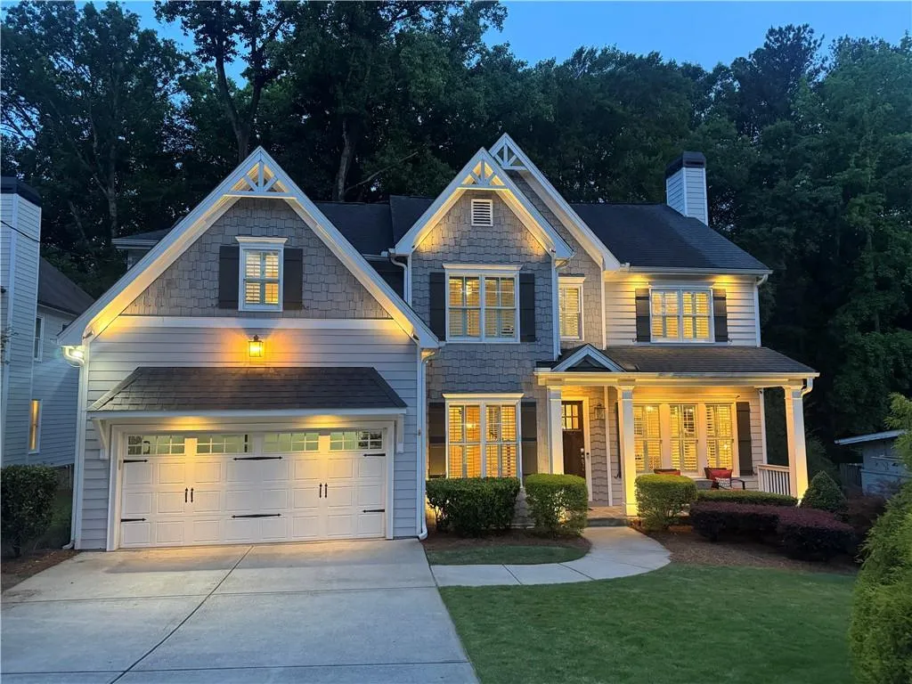 View of front of home at dusk, property featuring concrete driveway, a porch, a chimney, and a front lawn