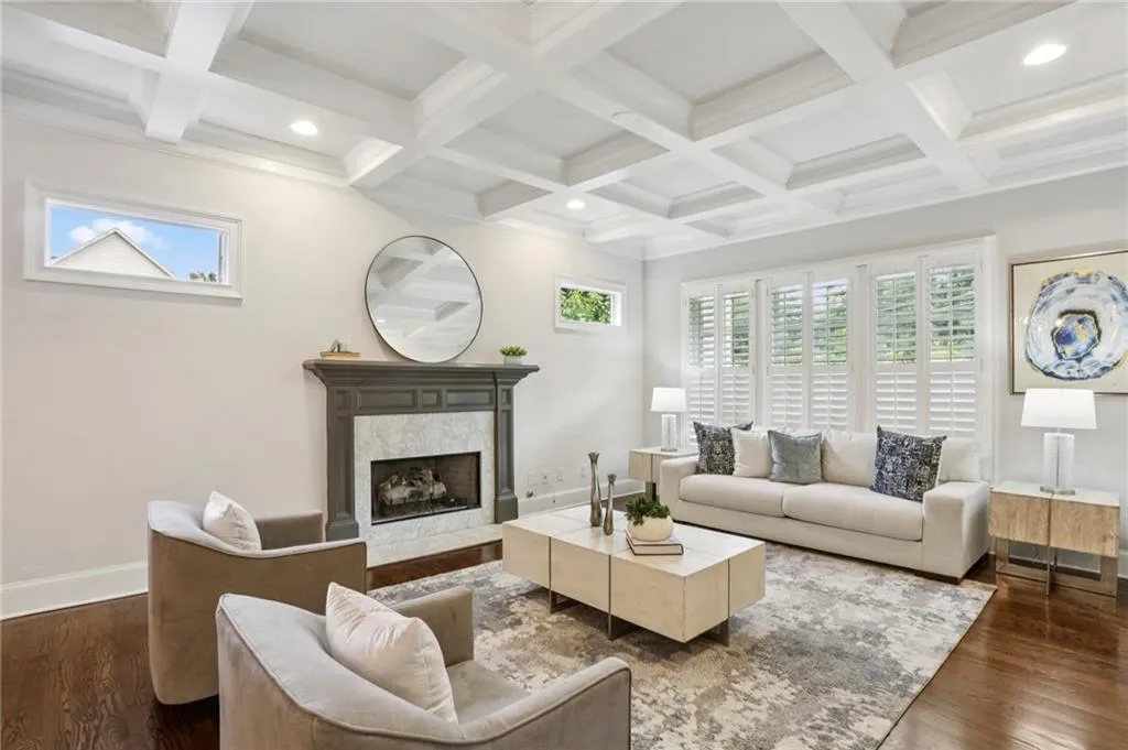 Living area featuring dark hardwood floors, beamed ceiling, a high end fireplace, healthy amount of natural light, and coffered ceiling