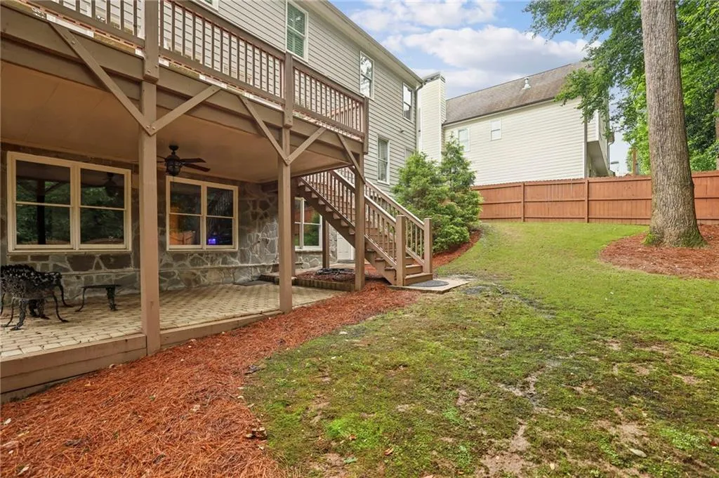 View of yard with a deck, a ceiling fan, stairs, and a patio