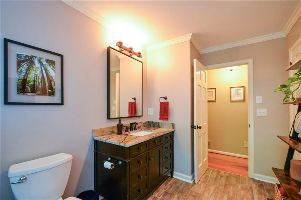 Bathroom with crown molding, wood-type flooring, vanity, and toilet Bathroom with crown molding, wood-type flooring, vanity, and toilet