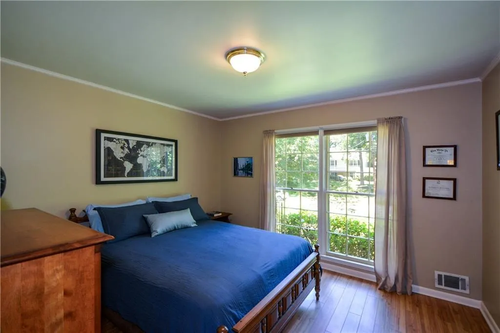 Bedroom with multiple windows, hardwood / wood-style floors, and ornamental molding Bedroom with multiple windows, hardwood / wood-style floors, and ornamental molding