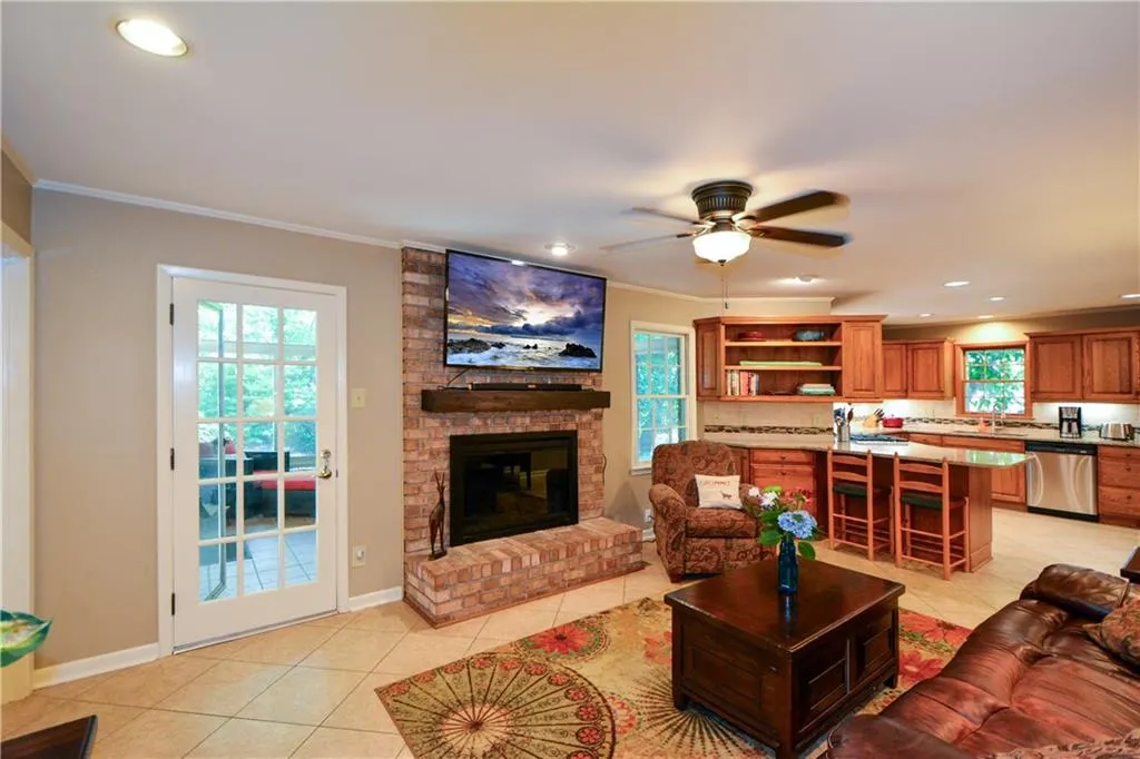Living room with ceiling fan, crown molding, a fireplace, brick wall, and light tile floors Living room with ceiling fan, crown molding, a fireplace, brick wall, and light tile floors