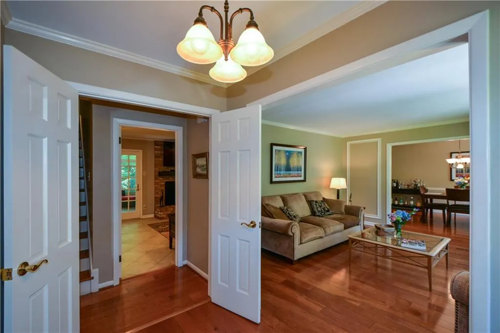 Living room with a notable chandelier, dark tile flooring, and crown molding Living room with a notable chandelier, dark tile flooring, and crown molding