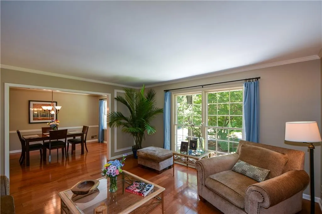 Living room with crown molding, an inviting chandelier, and hardwood / wood-style floors Living room with crown molding, an inviting chandelier, and hardwood / wood-style floors