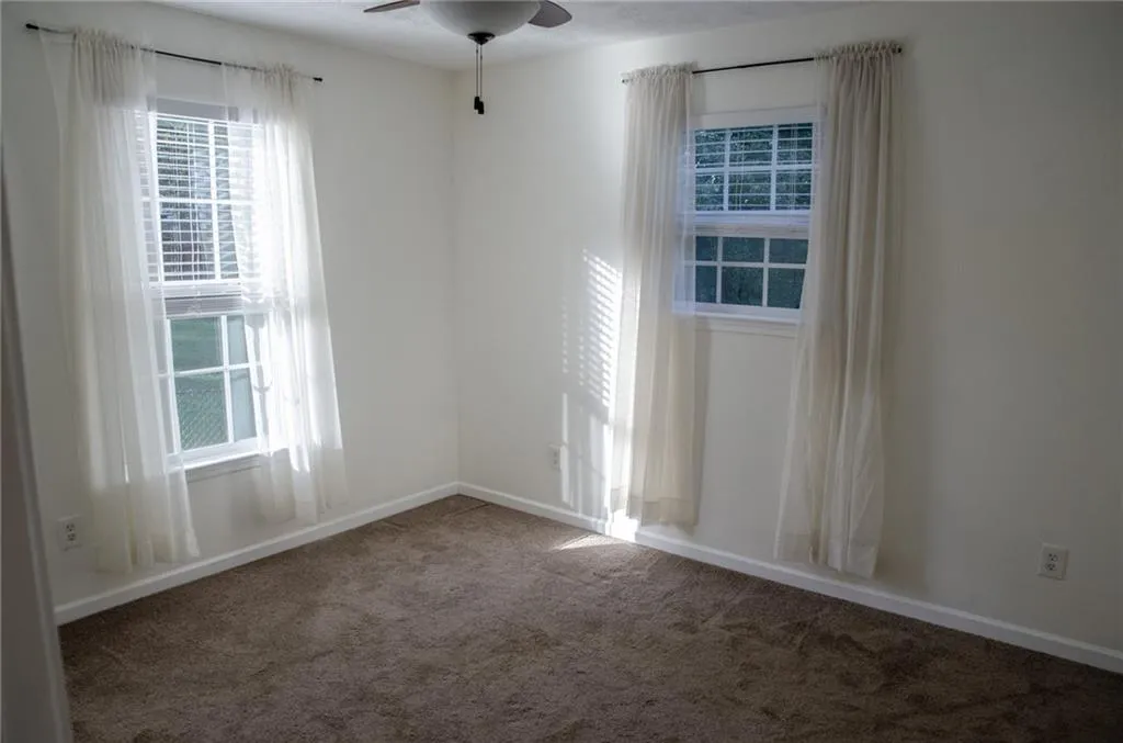 Carpeted spare room with baseboards and ceiling fan