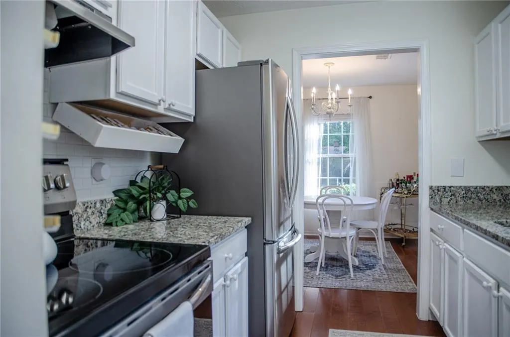 Kitchen featuring stainless steel range with electric cooktop, dark wood-type flooring, white cabinetry, a chandelier, and under cabinet range hood
