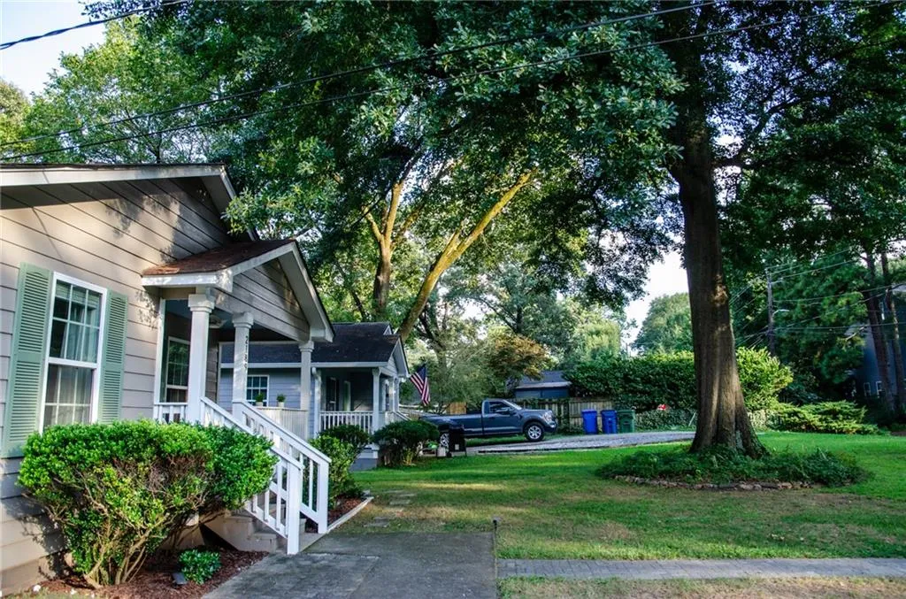View of grassy yard with covered porch and view of wooded area