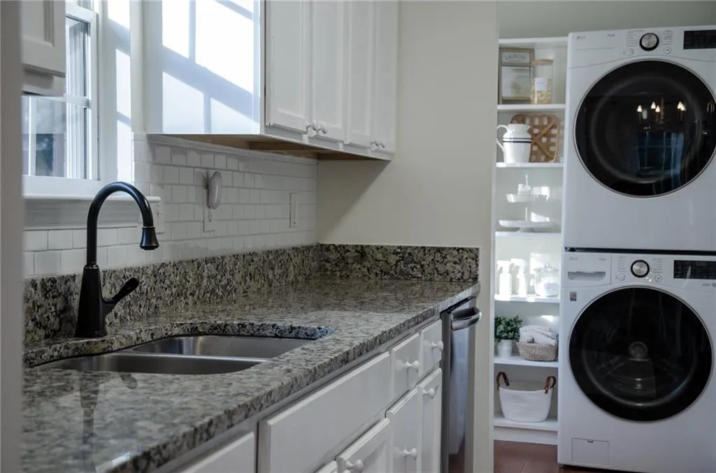 Laundry room with stacked washing machine and dryer and cabinet space
