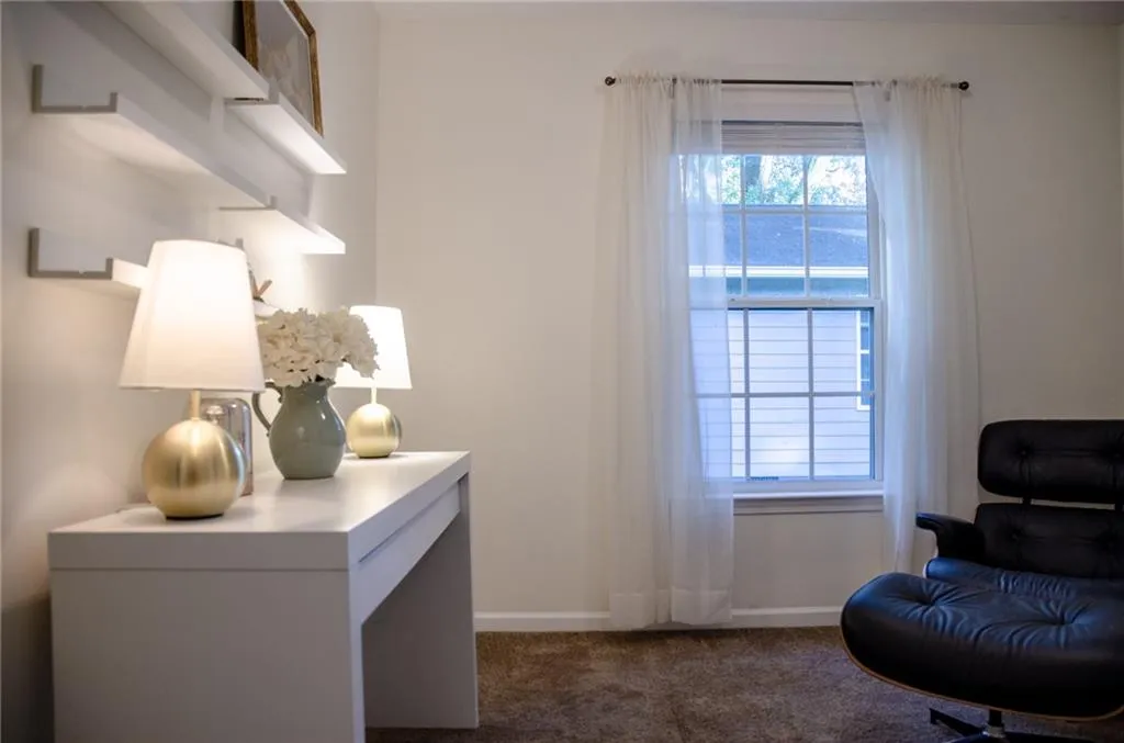 Sitting room with dark carpet and baseboards