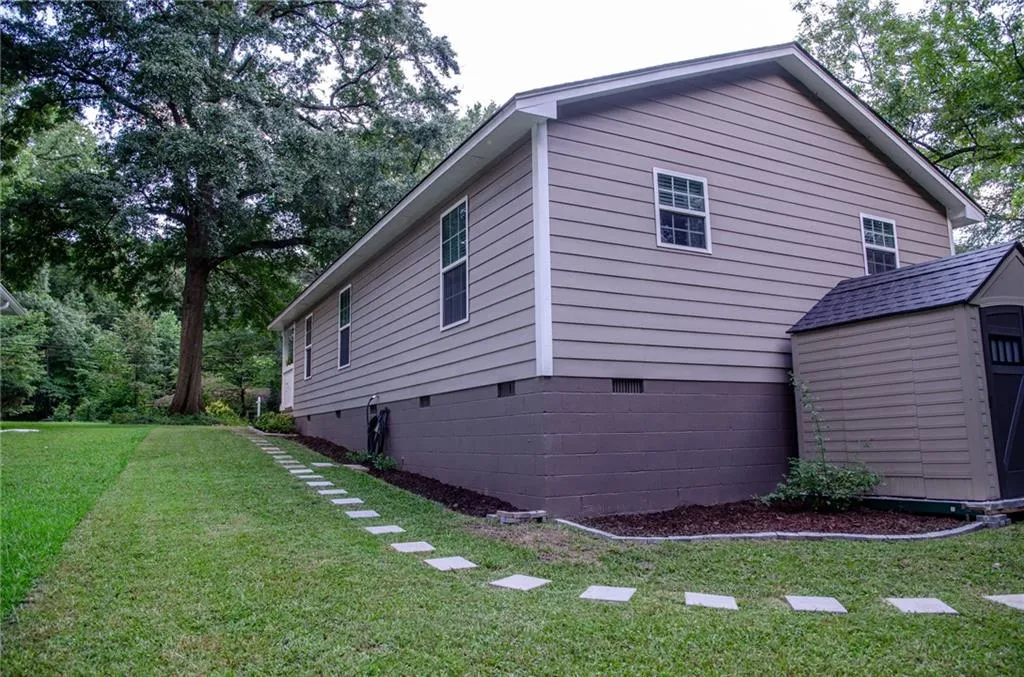 View of home's exterior with crawl space, a yard, and a shed