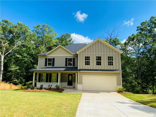 Two-story residence featuring a covered front porch, attached two-car garage, and a concrete driveway