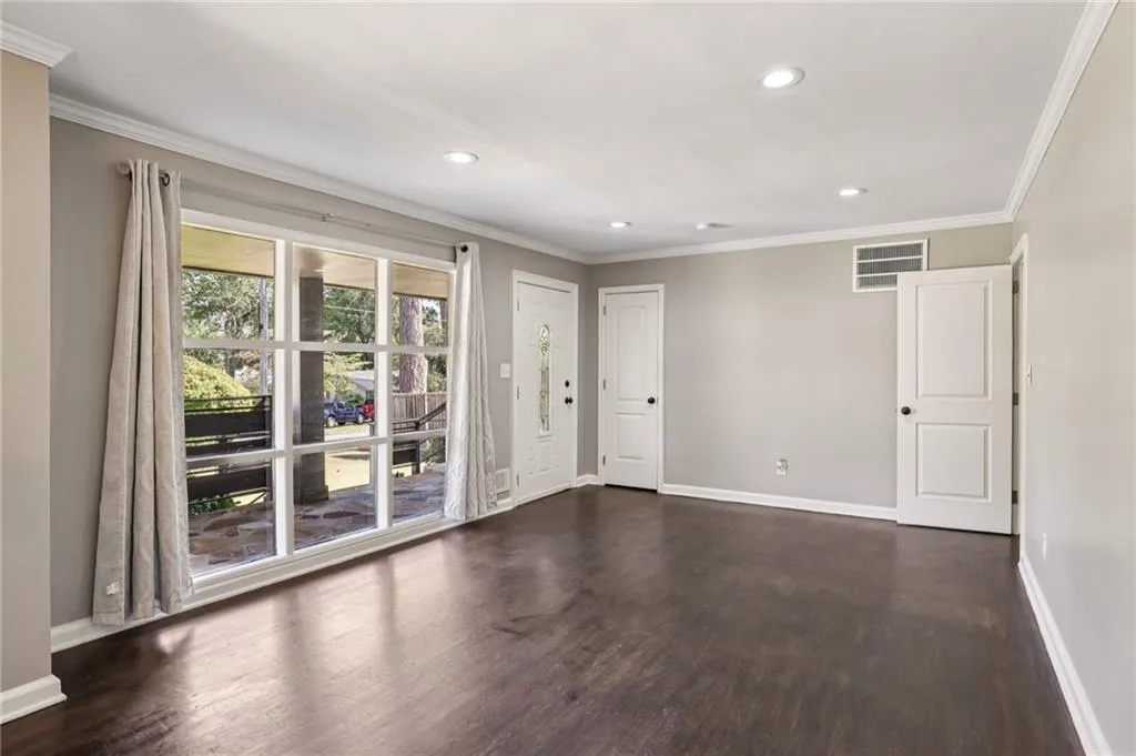 Empty room with crown molding, dark wood-style flooring, and recessed lighting