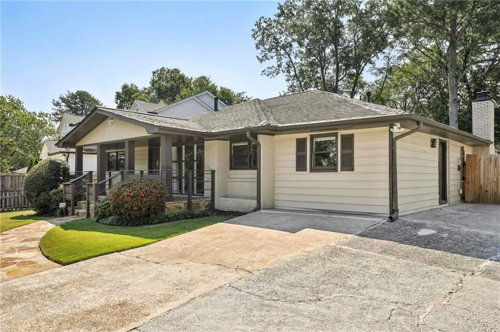 View of front of house with covered porch, a shingled roof, a chimney, and brick siding
