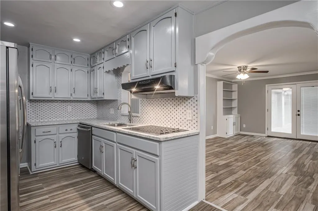 Kitchen includes stainless steel appliances, stone counters and tiled backsplash