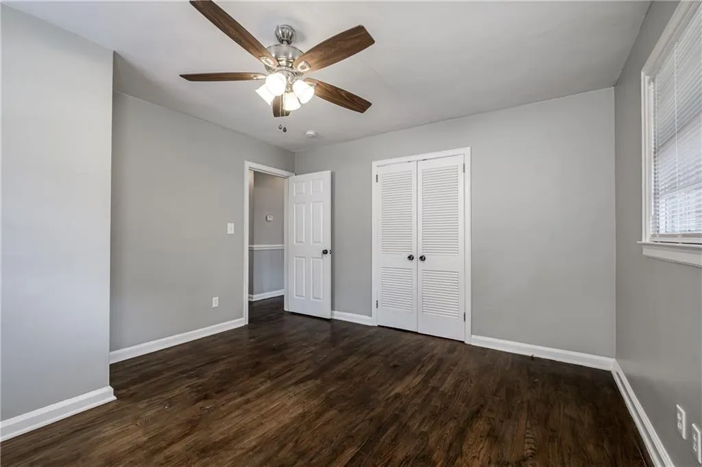 Unfurnished bedroom with dark wood-type flooring, a closet, and a ceiling fan