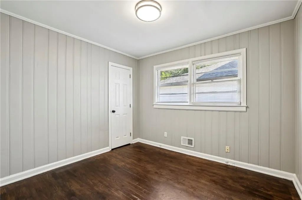 Unfurnished room with dark wood-type flooring and ornamental molding