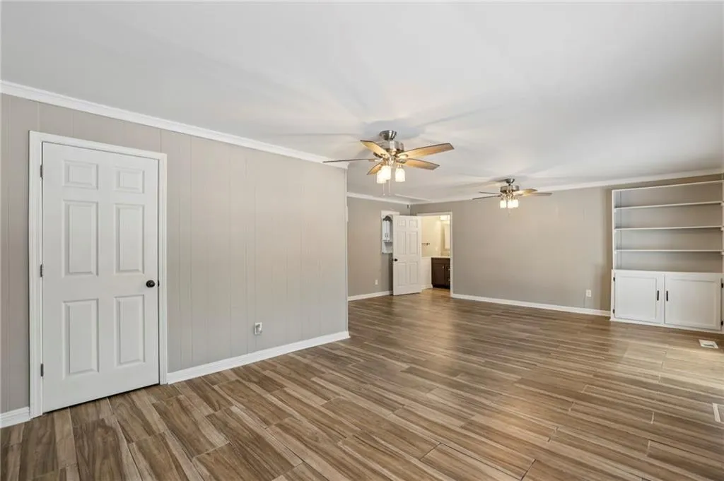 Unfurnished living room featuring crown molding, light wood finished floors, and ceiling fan