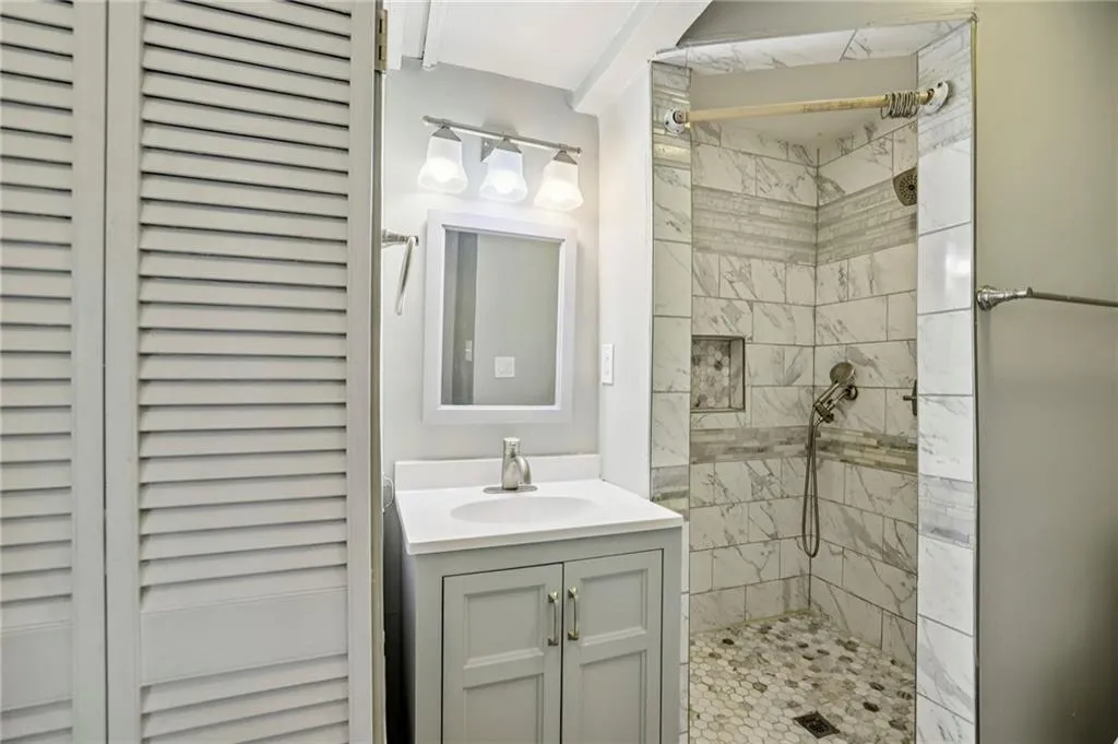Full bath featuring vanity, a stall shower, and a closet
