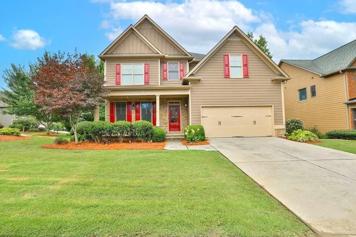 Two-story residence featuring a covered front porch, attached garage, and a concrete driveway