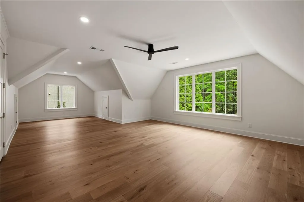 Spacious room featuring wood-finish flooring, multiple windows, a ceiling fan, and recessed lighting
