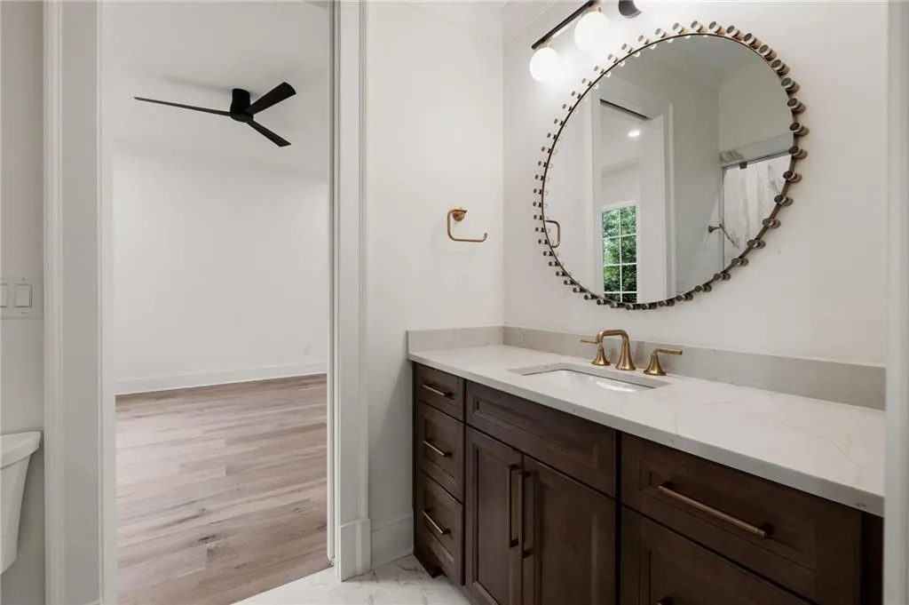 Steam Shower bathroom.Vanity with wood-finish cabinetry, light-toned countertop, under-mount sink, and brass-finish fixtures