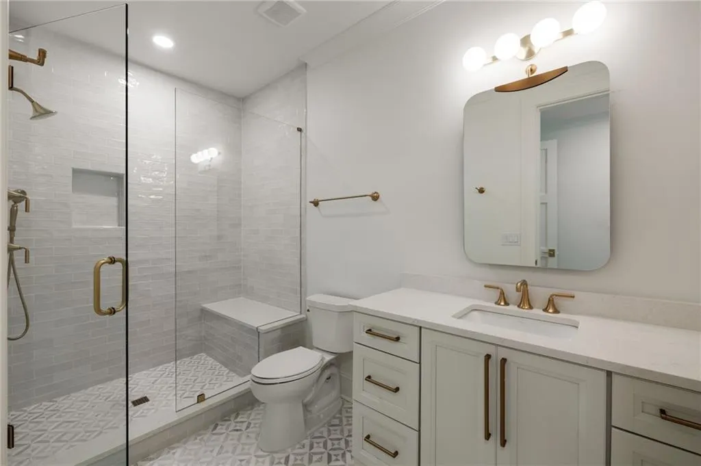 Upstairs Bathroom.Glass-enclosed shower with a built-in bench and recessed niche.