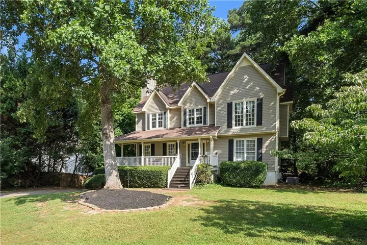 Two-story siding exterior with multiple gables, covered front porch, and mature landscaping