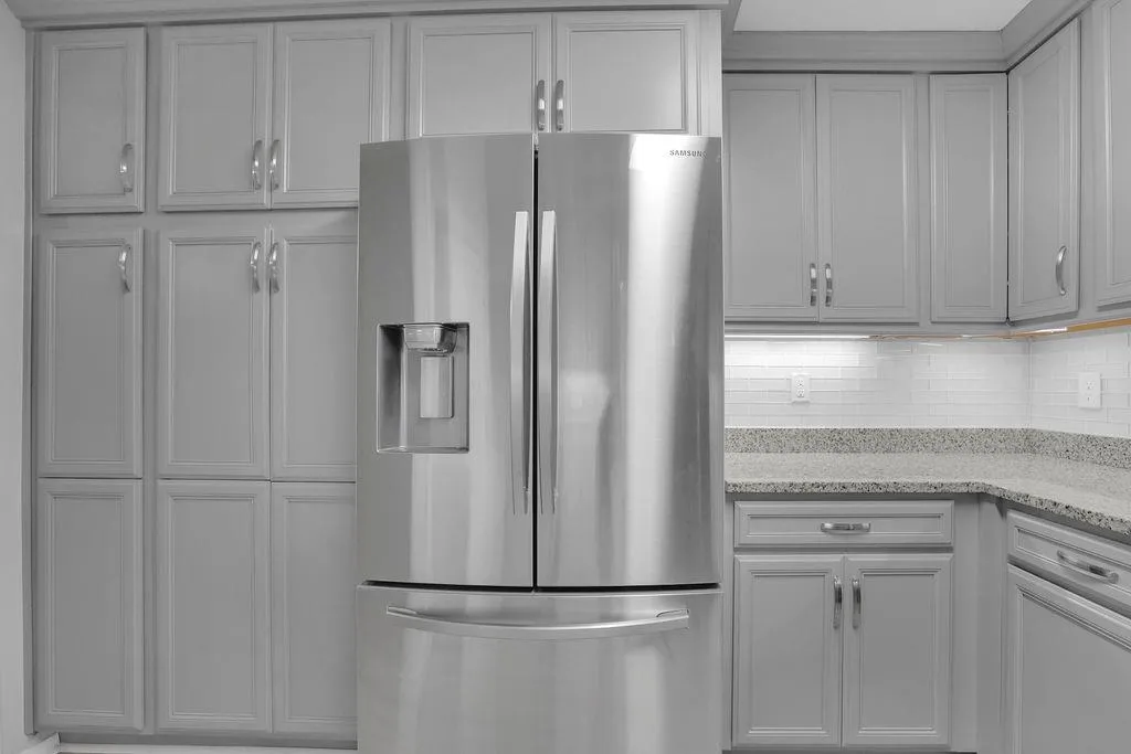 Kitchen featuring backsplash, stainless steel refrigerator with ice dispenser, and light stone counters