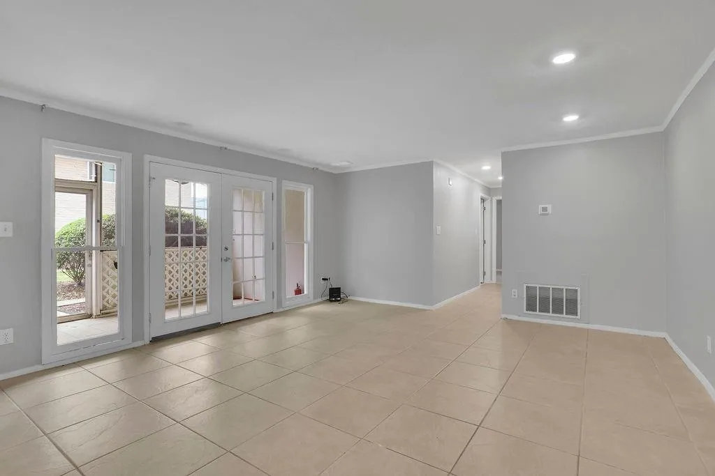 Tiled empty room with ornamental molding and french doors