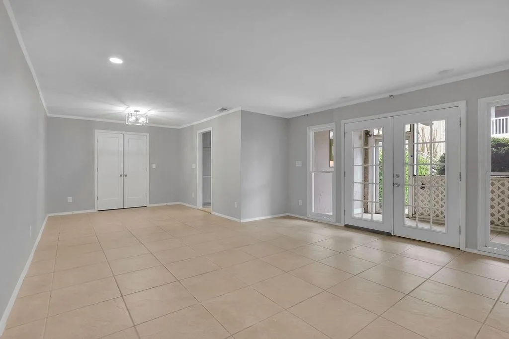 Tiled empty room featuring ornamental molding and french doors
