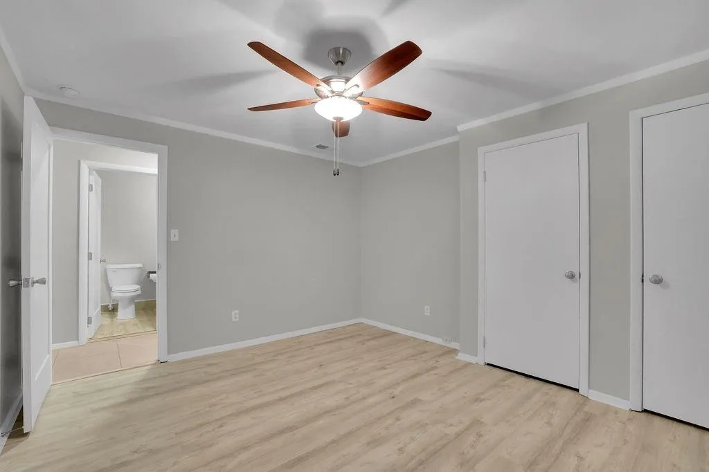 Unfurnished bedroom featuring light hardwood / wood-style floors, crown molding, two closets, and ceiling fan