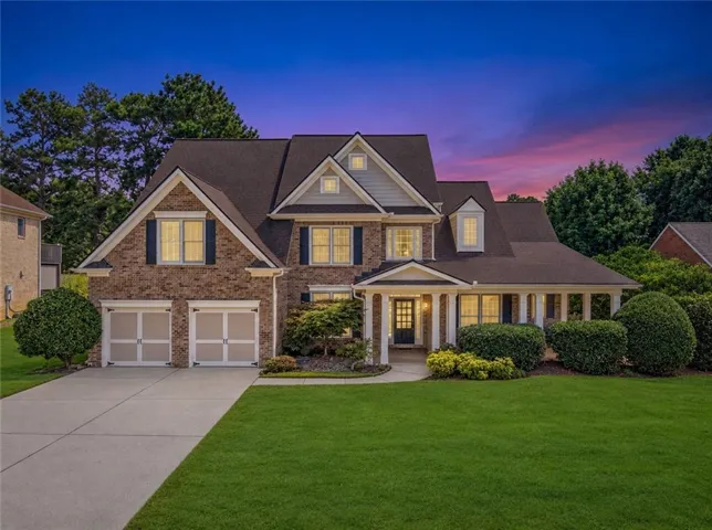 Brick and siding exterior with multiple gables, covered front porch, attached two-car garage, and concrete driveway