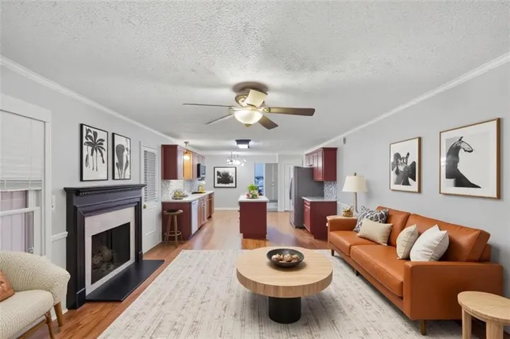 Open concept living area with wood-finish flooring, a ceiling fan, and a fireplace with a dark mantel