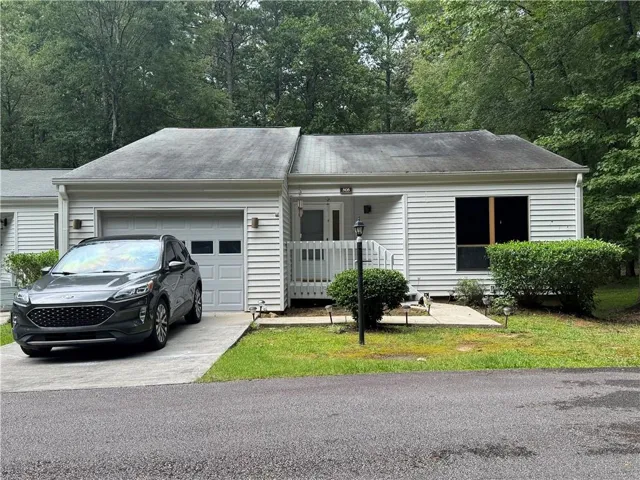 White siding exterior with an attached garage, paved driveway, and covered front entry