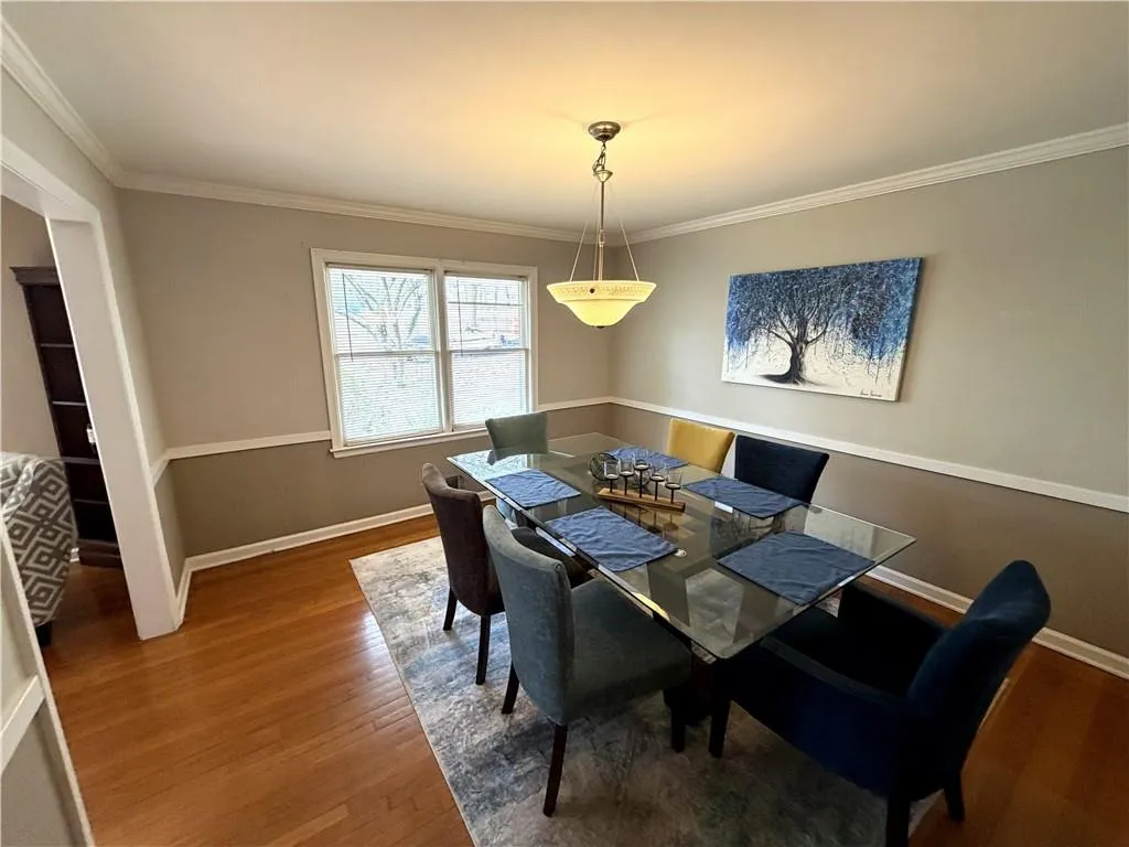 Dining space featuring wood finished floors and crown molding