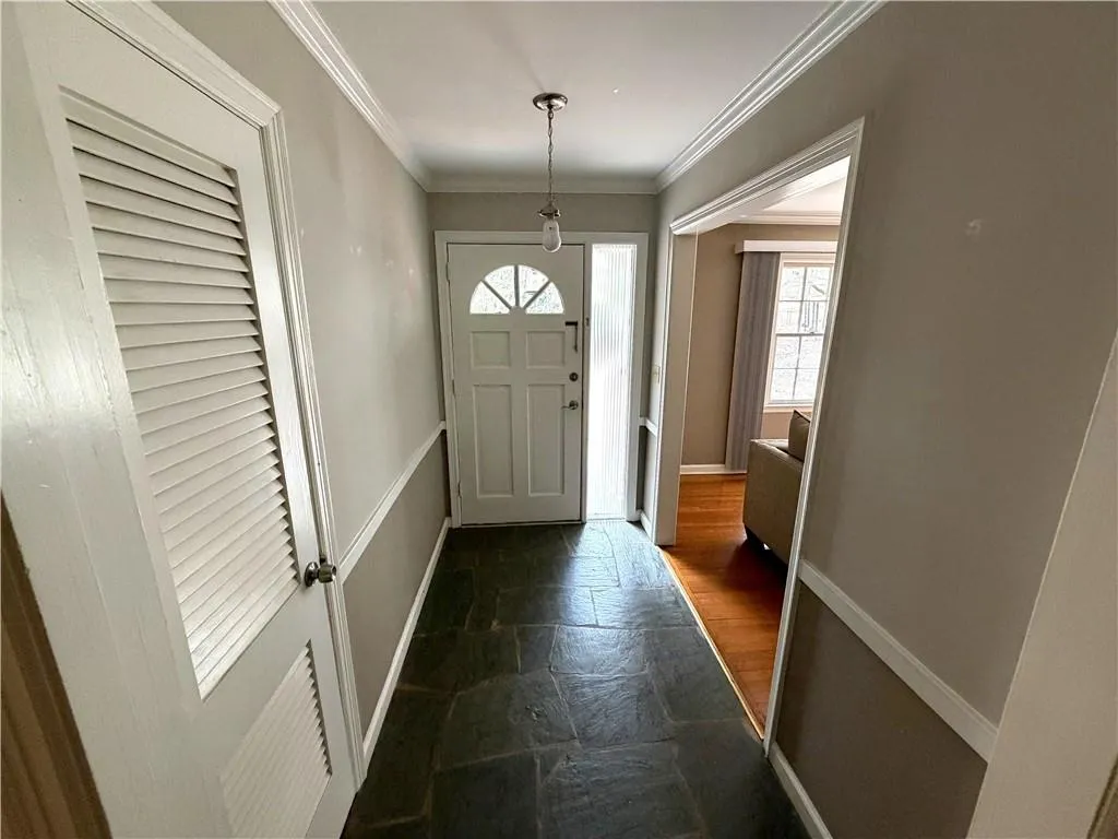 Foyer entrance featuring dark stone finish floors and ornamental molding