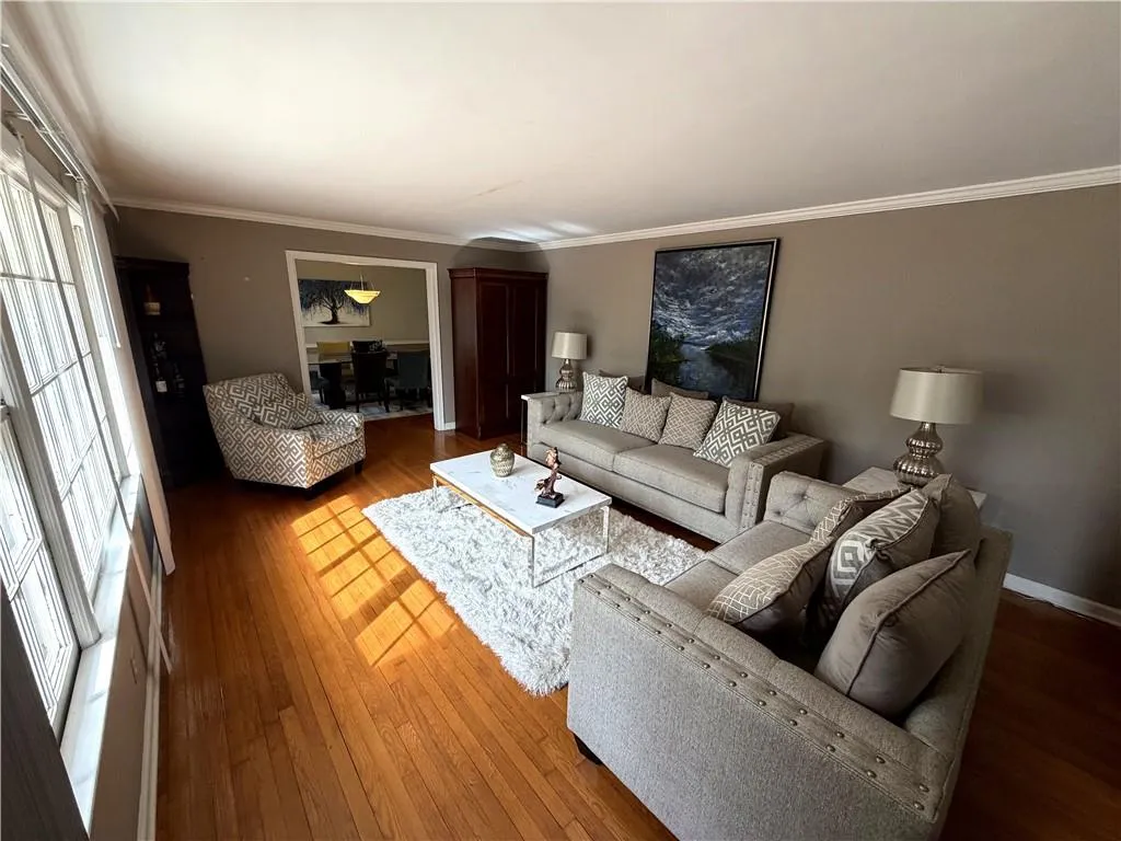 Living room featuring wood-type flooring and crown molding
