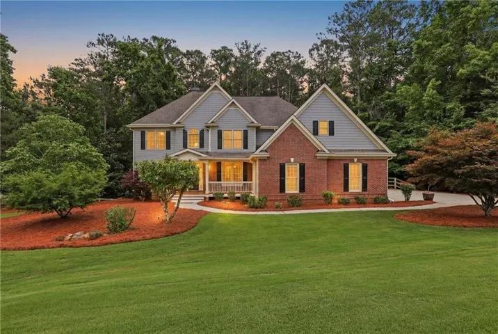 Traditional-style residence featuring brick and siding facade, covered front porch, a well-maintained lawn, and mature landscaping