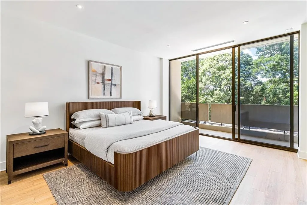 Floor-to-ceiling glass sliding doors, wood-finish flooring, recessed lighting, and a private balcony with metal railings