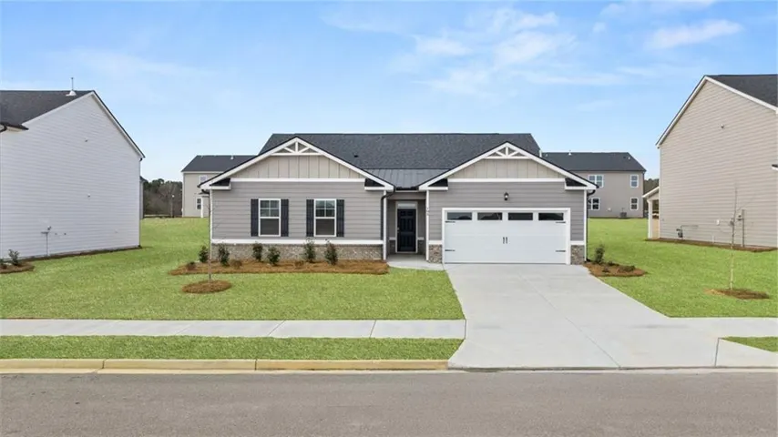 Contemporary ranch home with light gray siding, dark shutters, an attached garage, and a concrete driveway