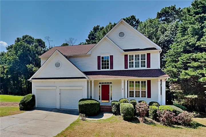 White siding exterior with a red front door, two-car garage, and red shutters