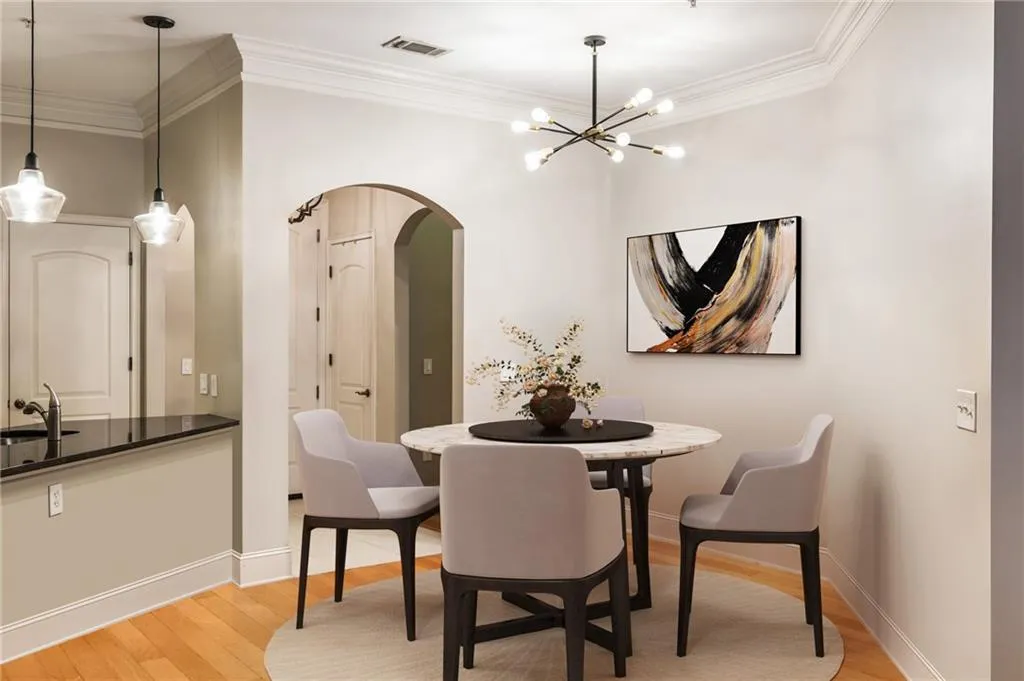 Dining area featuring arched walkways, light wood finished floors, ornamental molding, baseboards, and a chandelier