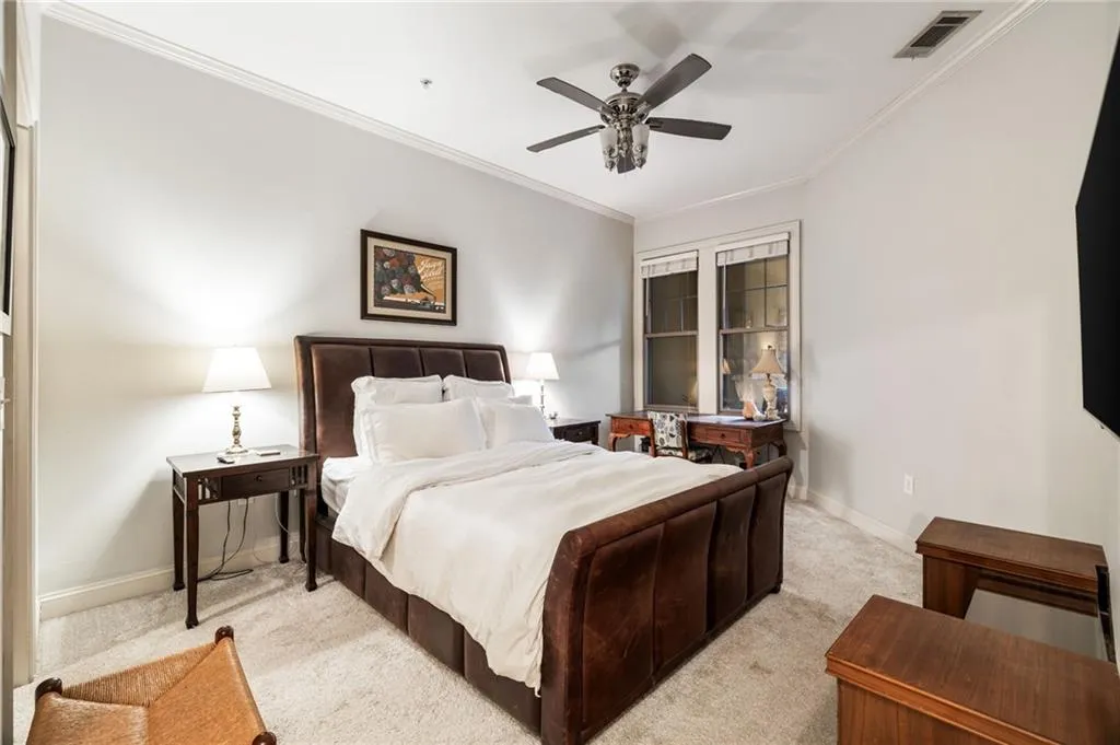 Bedroom featuring light colored carpet, baseboards, ornamental molding, and ceiling fan