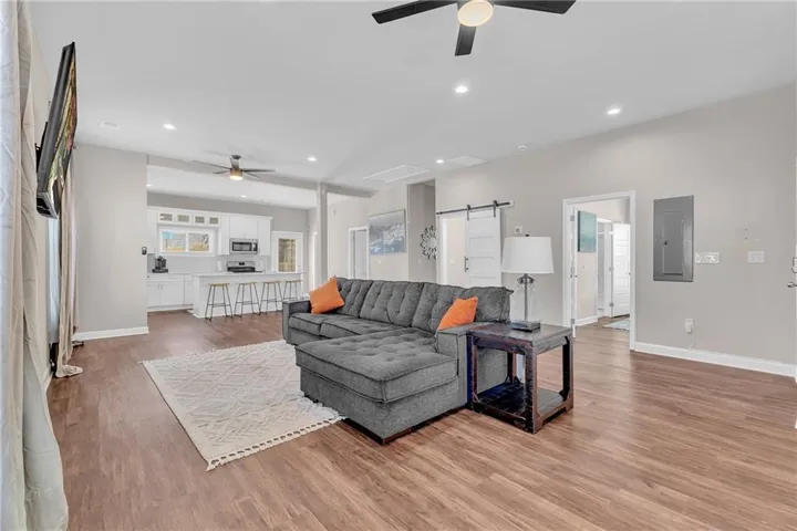 Spacious living area featuring wood-finish flooring, recessed lighting, and ceiling fans