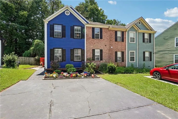 Multi-story property featuring a blue siding facade, brick siding, and light green siding
