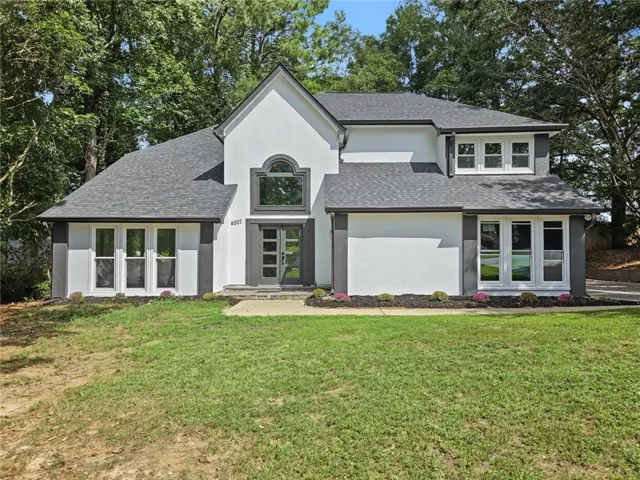 Stucco exterior with contrasting trim, multi-pane windows, arched transom window, and a modern entry door