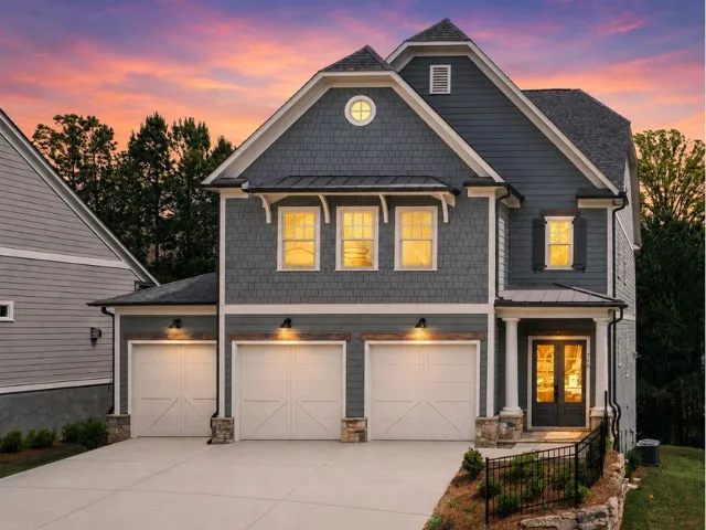 Craftsman-style exterior featuring a combination of horizontal siding and shake shingles, a prominent three-car garage with carriage-style doors, a covered entry porch with columns, and a concrete driveway
