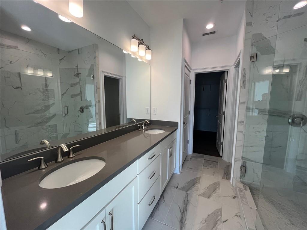 Bathroom with double vanity, tile flooring, and walk in shower